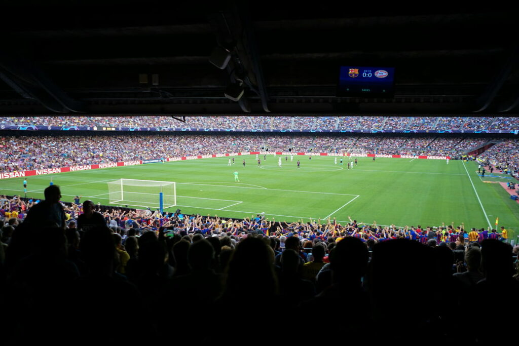 Football stadium lit at night with a crowd watching a match, representing cross-border investment in international sports